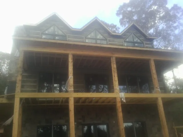Dormers and porch framing on a large log home under construction — Roof Coating work by our crew in Macksburg