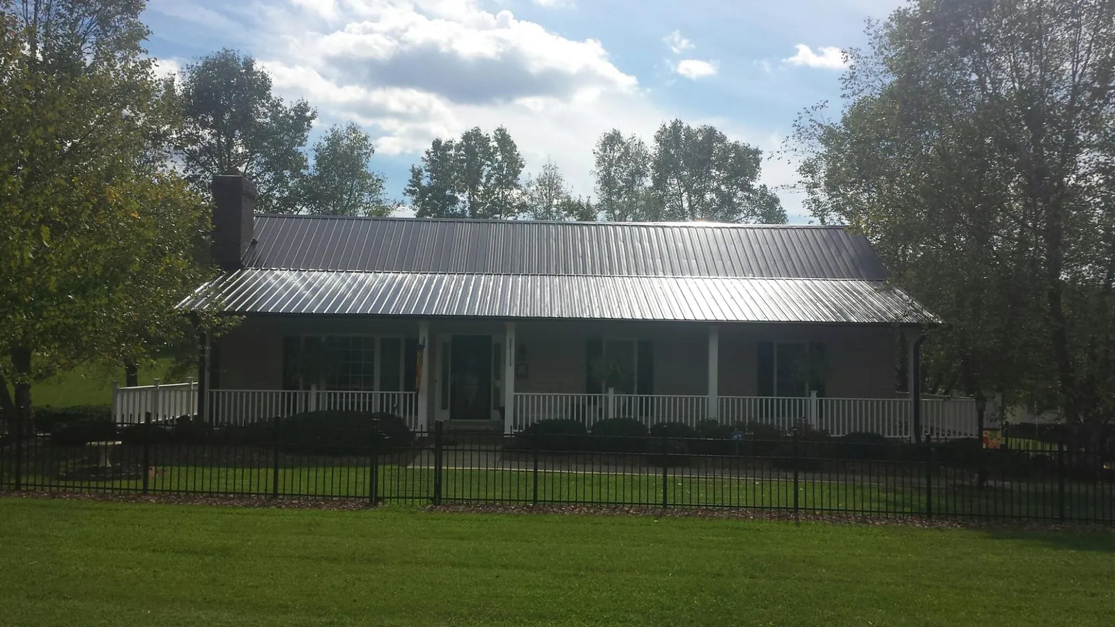 Gray metal roof on a brick ranch with a full width front porch — Gutter Guard Installation work by our crew in Macksburg