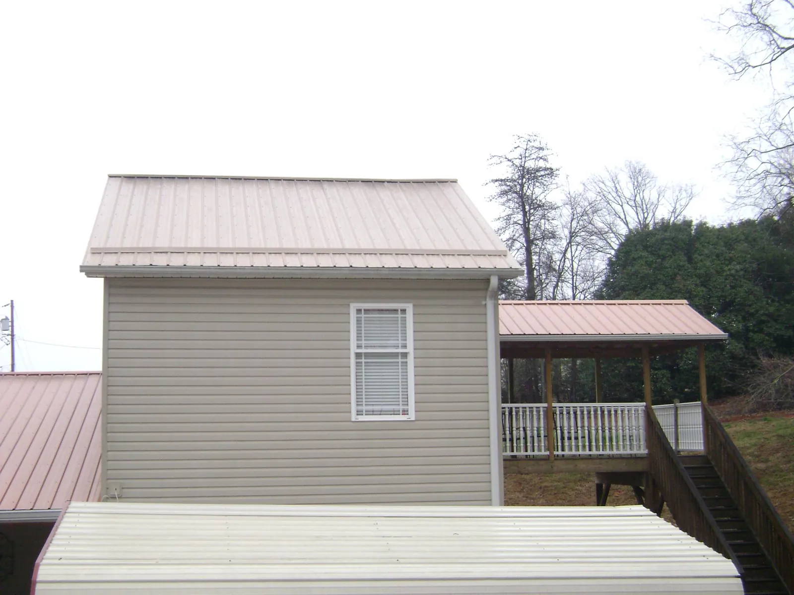 Tan metal roofs on a two story addition and attached porch, from a Roof Replacement job in Macksburg