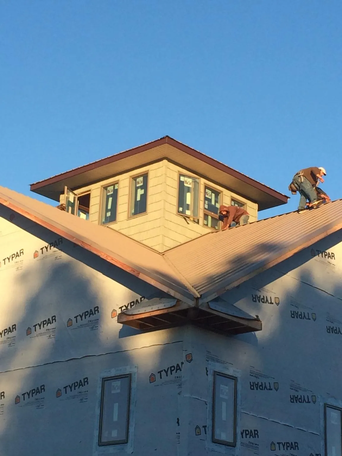 Roofers working around a rooftop cupola on a new metal roof at sunset — Roof Waterproofing in Macksburg by Roofing Brothers
